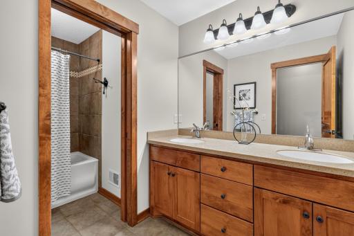 Full Bathroom features a large alder vanity cabinet with two sinks, ceramic tile flooring and pocket door access to separate tub and toilet room