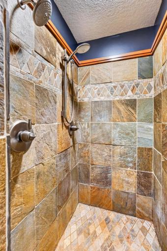 Custom walk-in shower features and additional hand shower and slate tile surround