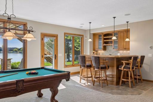 The wet bar is enhanced by heated floors, expansive counter space, and seating, with easy access to outdoor living areas