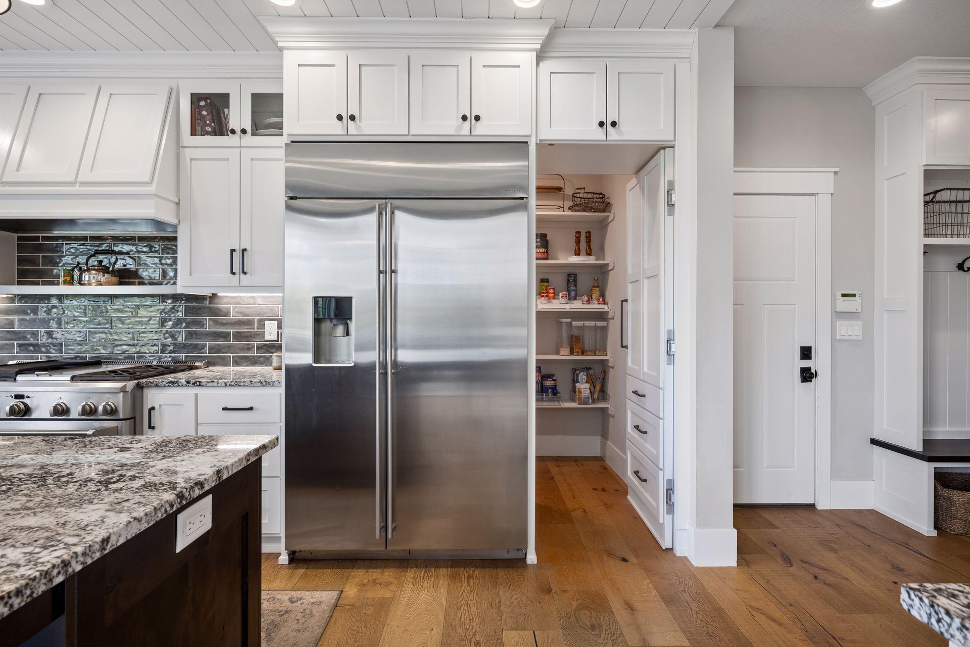 A hidden pantry door discreetly tucked beside the refrigerator adds both charm and functionality, seamlessly blending into the custom cabinetry for a clean look.