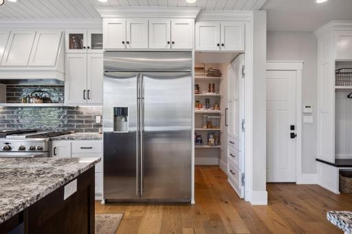 A hidden pantry door discreetly tucked beside the refrigerator adds both charm and functionality, seamlessly blending into the custom cabinetry for a clean look.