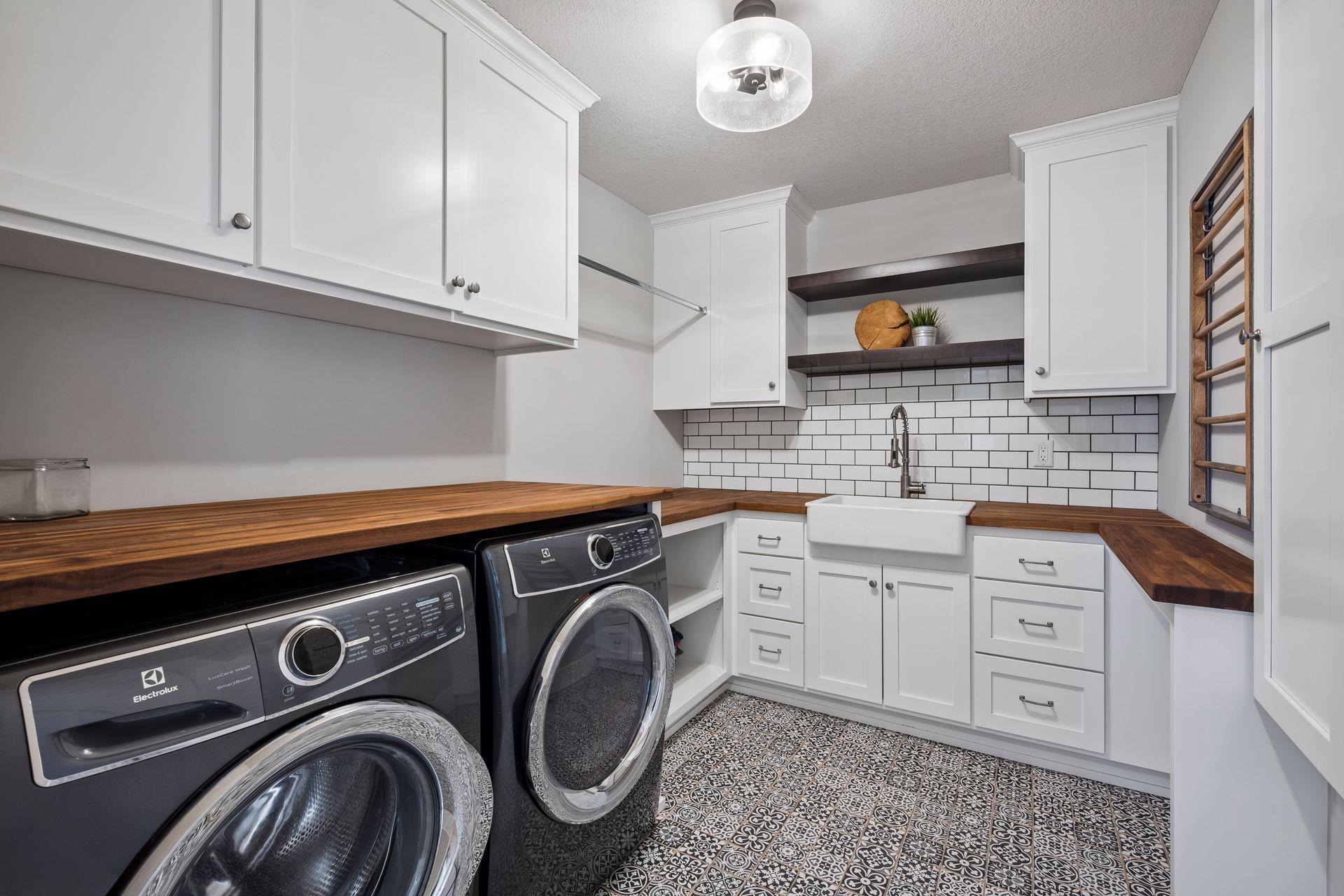 An exceptional upper-level laundry room features custom built-ins and a farmhouse sink, combining beauty, functionality, and thoughtful design.