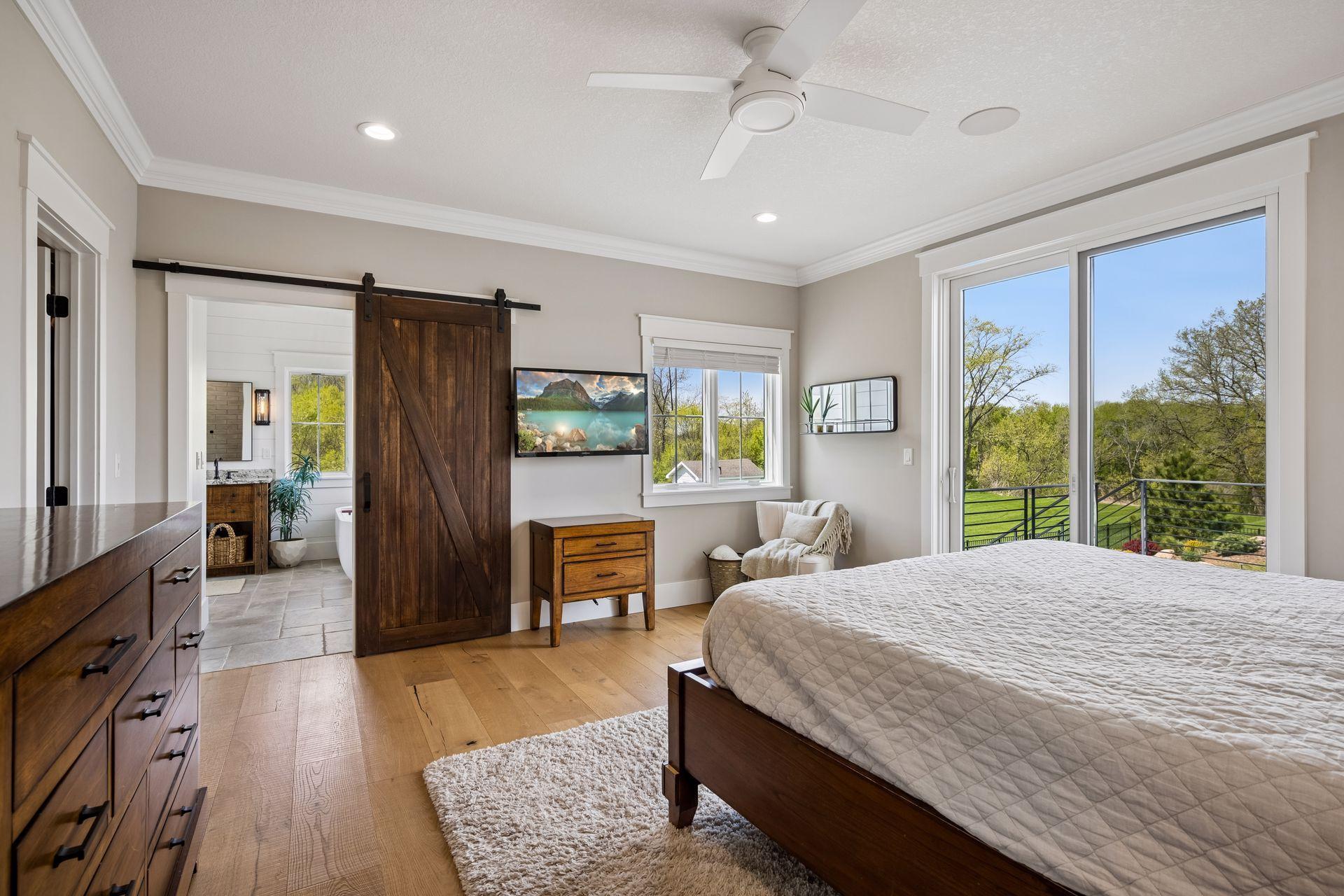 The luxurious primary retreat features elegant tray ceilings, built-in surround sound, and a stylish barn door leading to the spa-inspired ensuite bath.