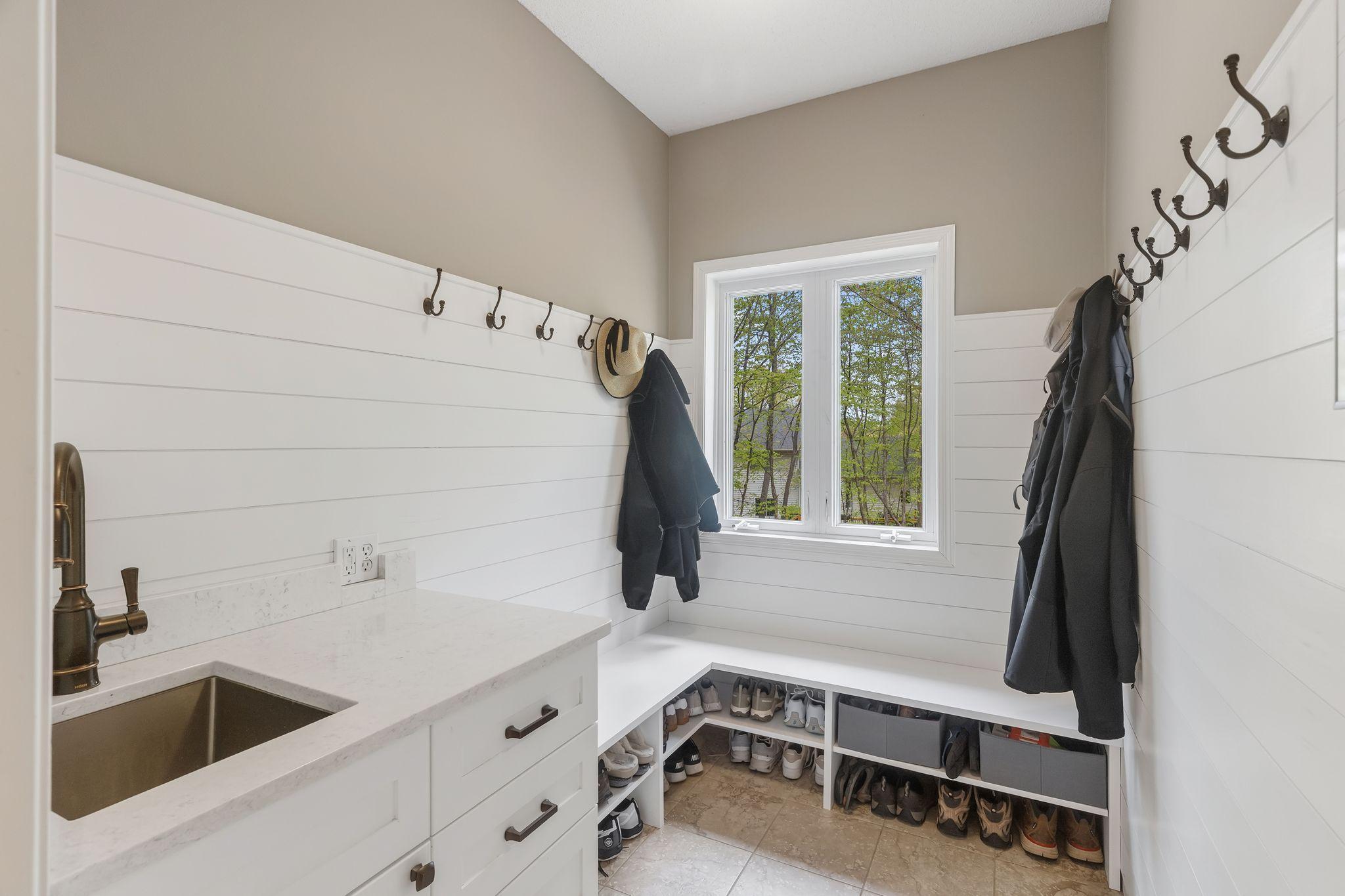 Updated mudroom with custom cabinetry, shiplap, sink and bench that can be closed off using the sliding “barn door”