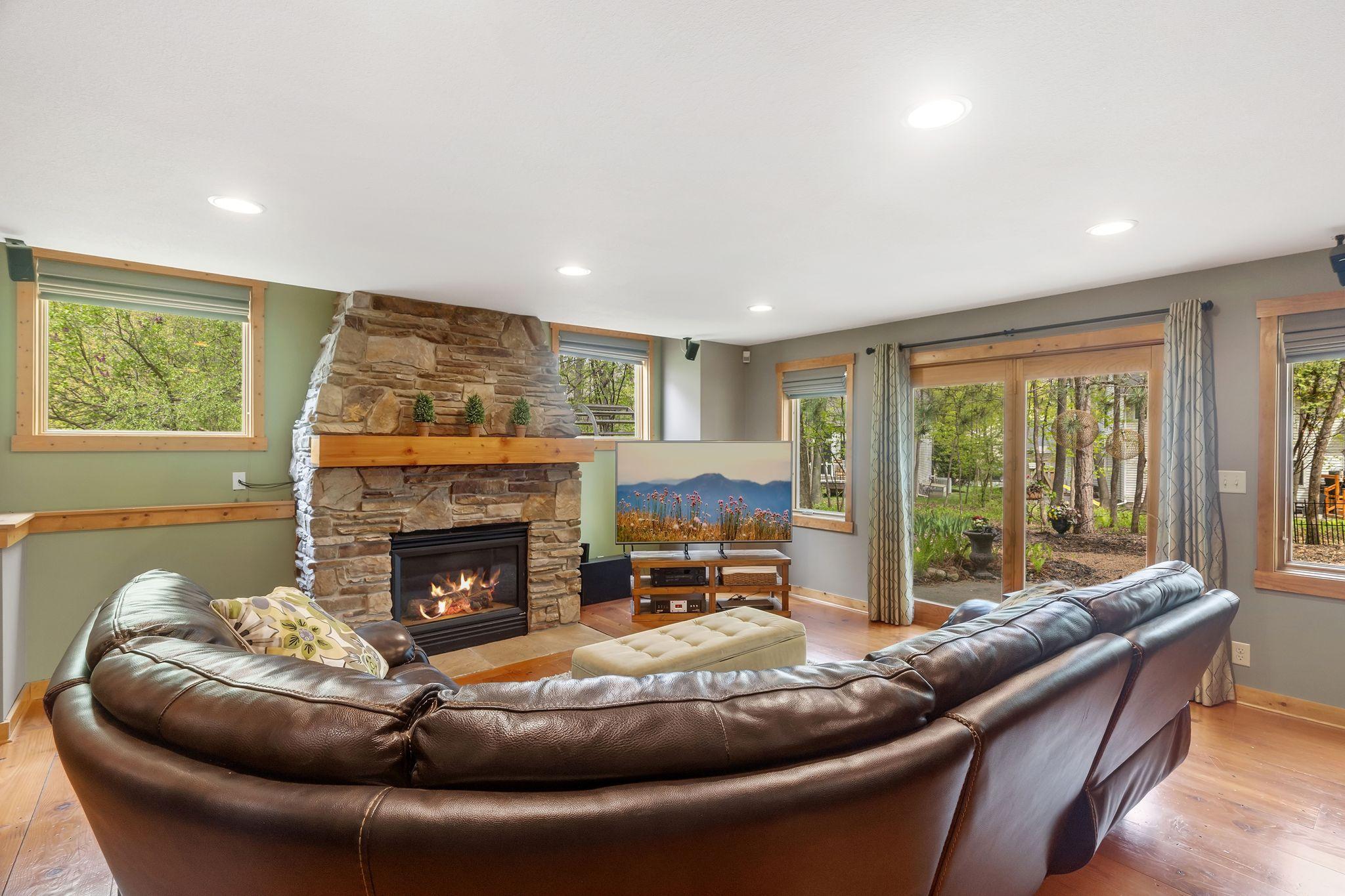 Warm and inviting walkout lower level amusement room with reclaimed wood floors, and a beautiful fireplace