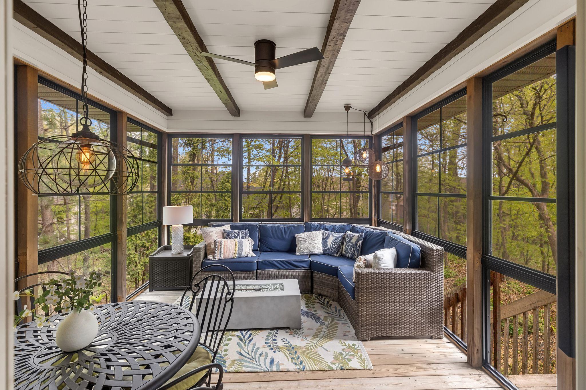 Stunning screened porch featuring SunSpace windows, shiplap accents, wood beams, and a ceiling fan—creating a cozy retreat you can enjoy nearly year-round.