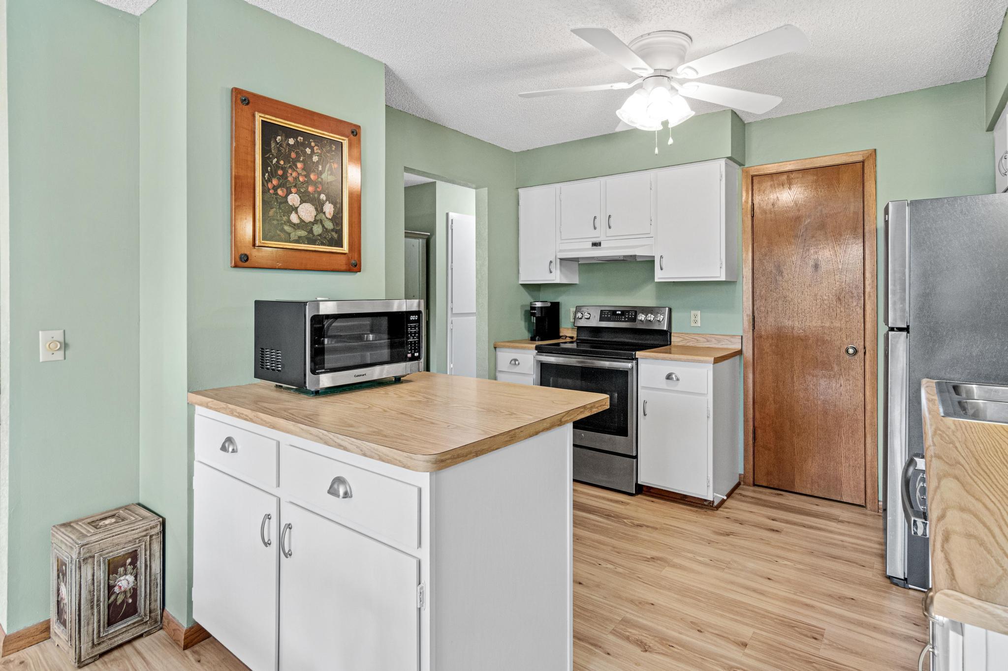 The kitchen features an updated vinyl floor, a full pantry, a broom closet, and stainless steel appliances. The dishwasher was replaced in 2025, the refrigerator in 2021, and convection stove in 2019.