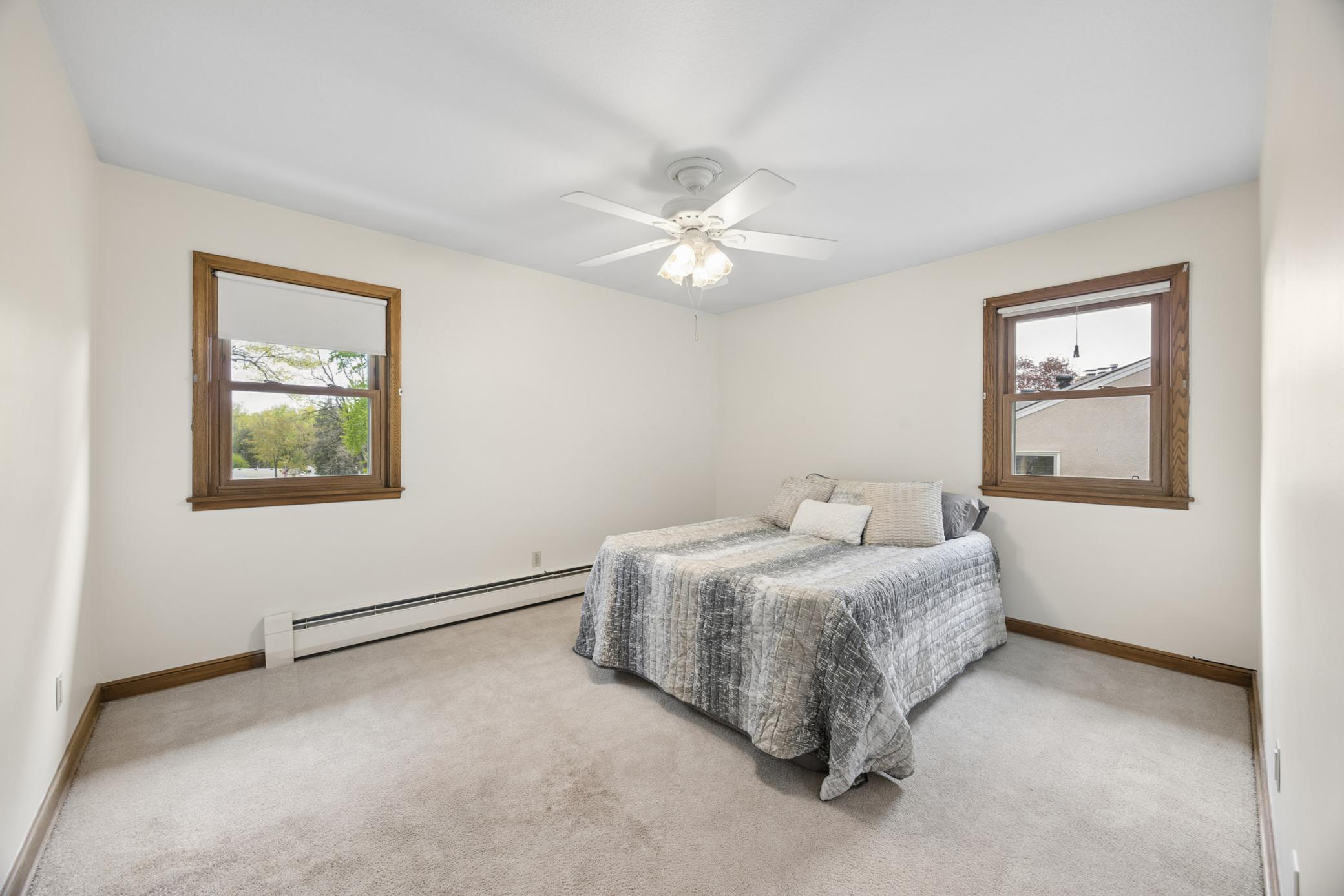 The primary bedroom shows off two nice windows and a lighted ceiling fan.