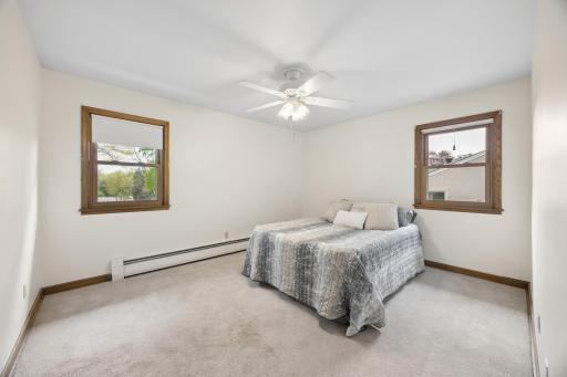 The primary bedroom shows off two nice windows and a lighted ceiling fan.