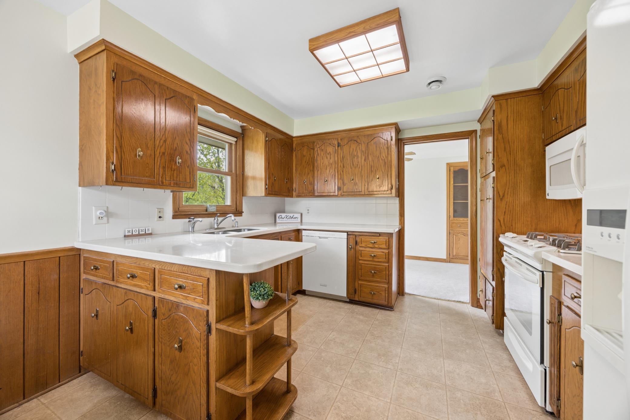 Bright and functional kitchen featuring abundant solid wood cabinetry, generous counter space, and a convenient center peninsula with open shelving.