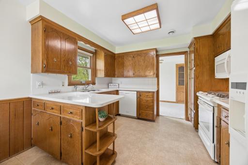 Bright and functional kitchen featuring abundant solid wood cabinetry, generous counter space, and a convenient center peninsula with open shelving.