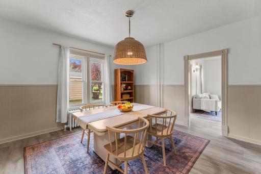 The formal dining room showcases statement lighting and classic wood-paneled wainscoting, adding warmth and detail, while continuous flooring throughout the main level creates a seamless, cohesive feel.