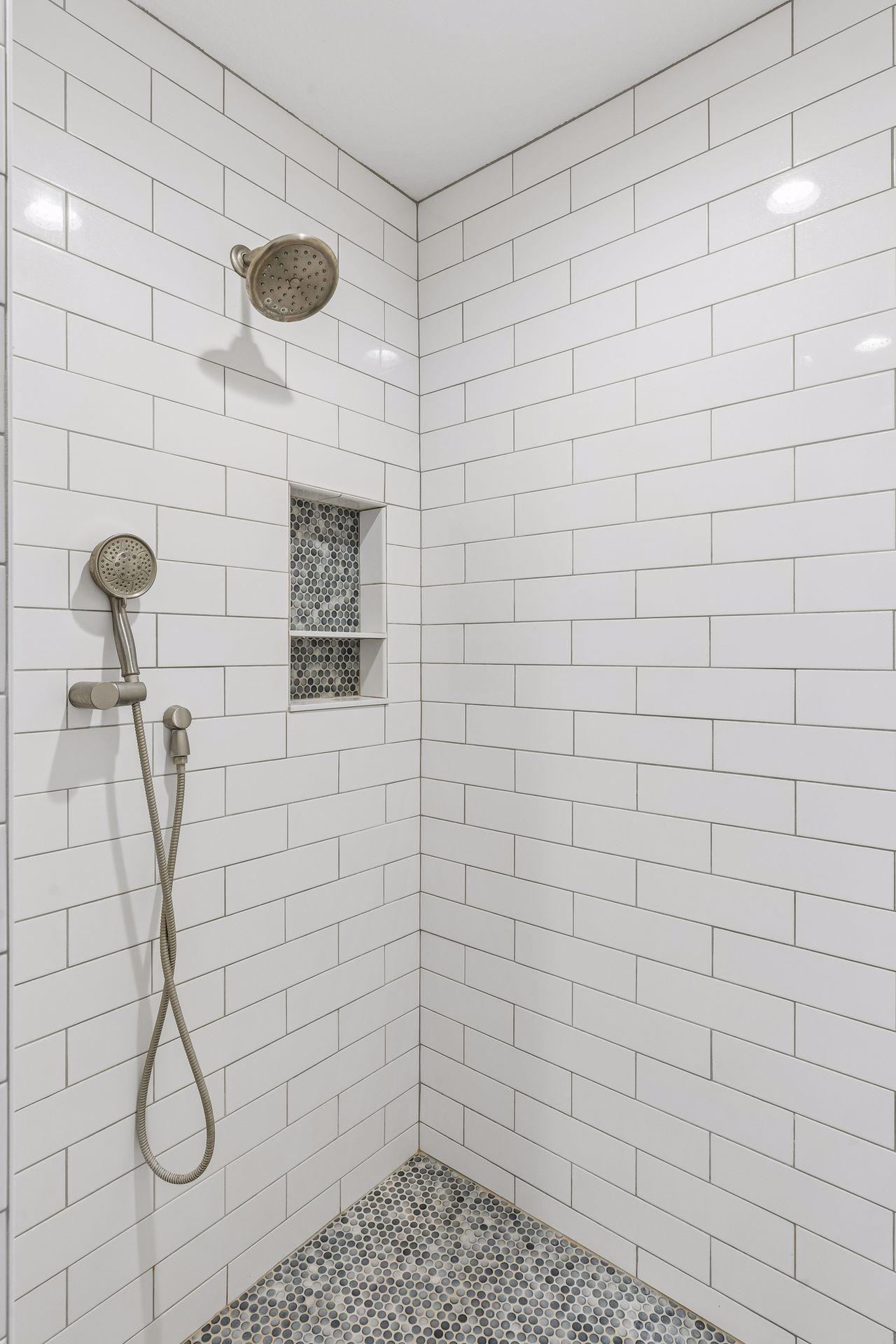 Large walk-in shower with tile and dual shower heads.