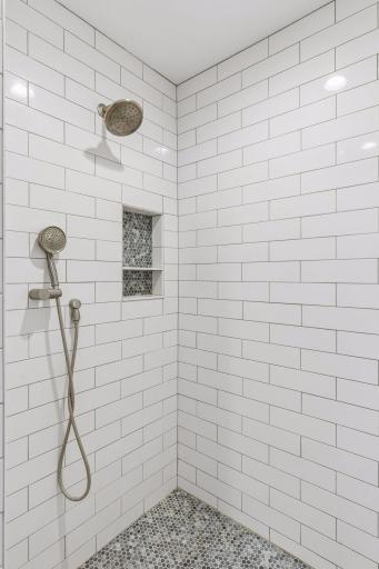 Large walk-in shower with tile and dual shower heads.