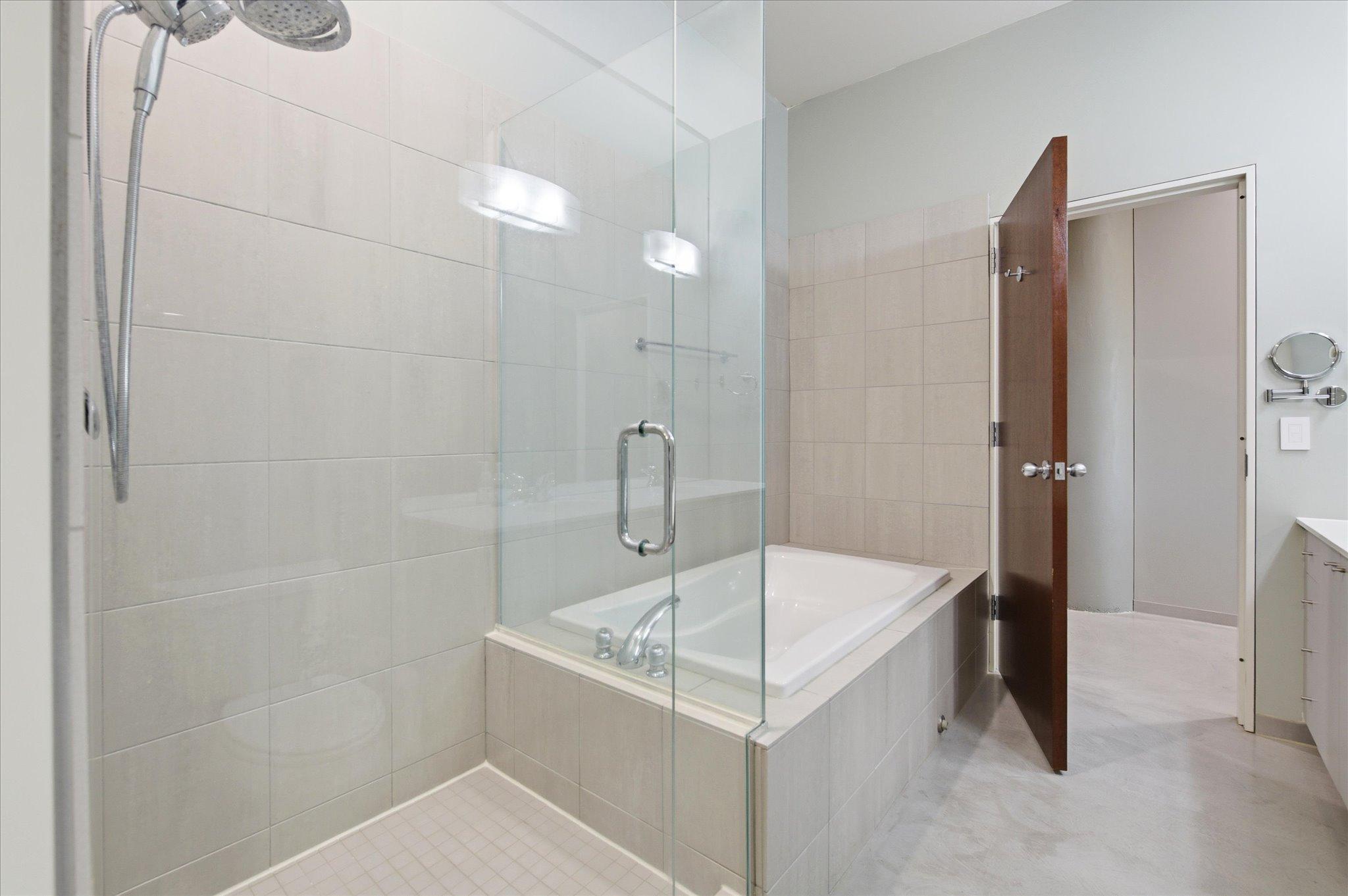 Contemporary bathroom with glass shower doors and a full bathtub for comfort and style.
