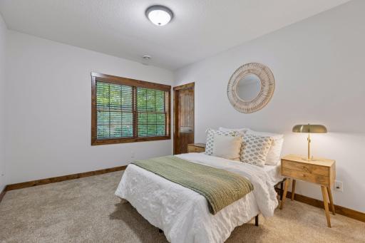 Private lower-level bedroom offers a peaceful retreat for family or guests, featuring generous proportions, warm finishes, and serene views. Thoughtfully designed to provide comfort, privacy, and the elevated feel expected in a luxury home.
