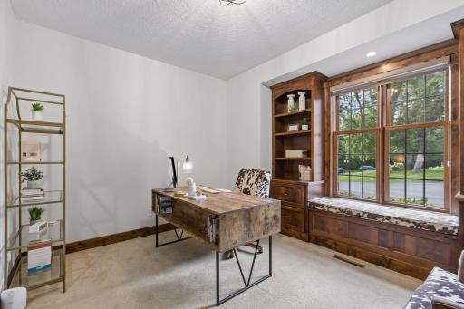 A private main-level office blends beauty and function with custom built-ins, a window seat, and picturesque views. Elegant sliding barn doors create a refined workspace designed for productivity, inspiration, and everyday flexibility.