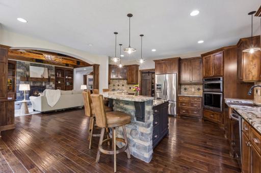 Warm, welcoming, and crafted with exceptional attention to detail, this open-concept gathering space centers around a stunning chef's kitchen with a stone-wrapped island, custom cabinetry, and seamless flow to the great room, where memories are made.