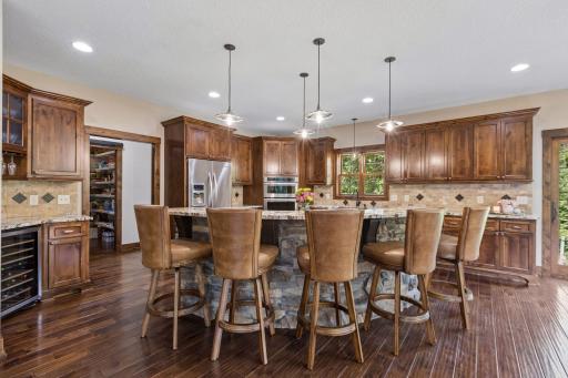 A culinary showpiece designed for entertaining, featuring custom alder cabinetry, rich granite surfaces, a striking stone-wrapped island, walk-in pantry, and premium appliances. Thoughtfully crafted for both grand gatherings and everyday luxury.