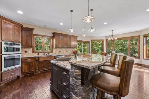 Where family gathers and memories are made, this stunning kitchen showcases a copper farmhouse sink, designer lighting, elegant tile backsplash, and beverage station, creating the perfect backdrop for everyday moments and special occasions