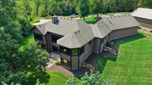 Aerial view of landscape with home and outbuilding surrounded by nature.