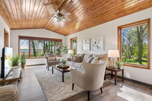 Vaulted wood ceilings, expansive windows, and tranquil lake views create a warm yet sophisticated living space filled with natural light.