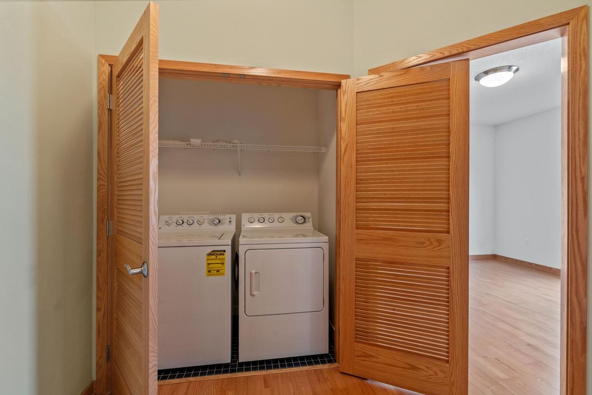 The laundry is at the end of the hall. Out of the way. There is also a cart that stays with the unit for hauling your groceries up from the garage.