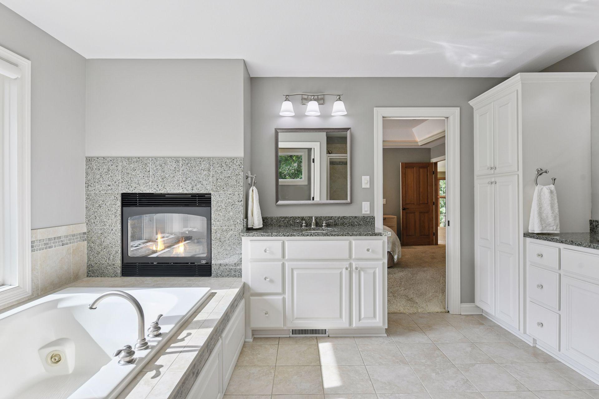 The large primary bathroom has a two-sided fireplace, jacuzzi tub, double sinks, and separate walk-in shower, and walk in closet.