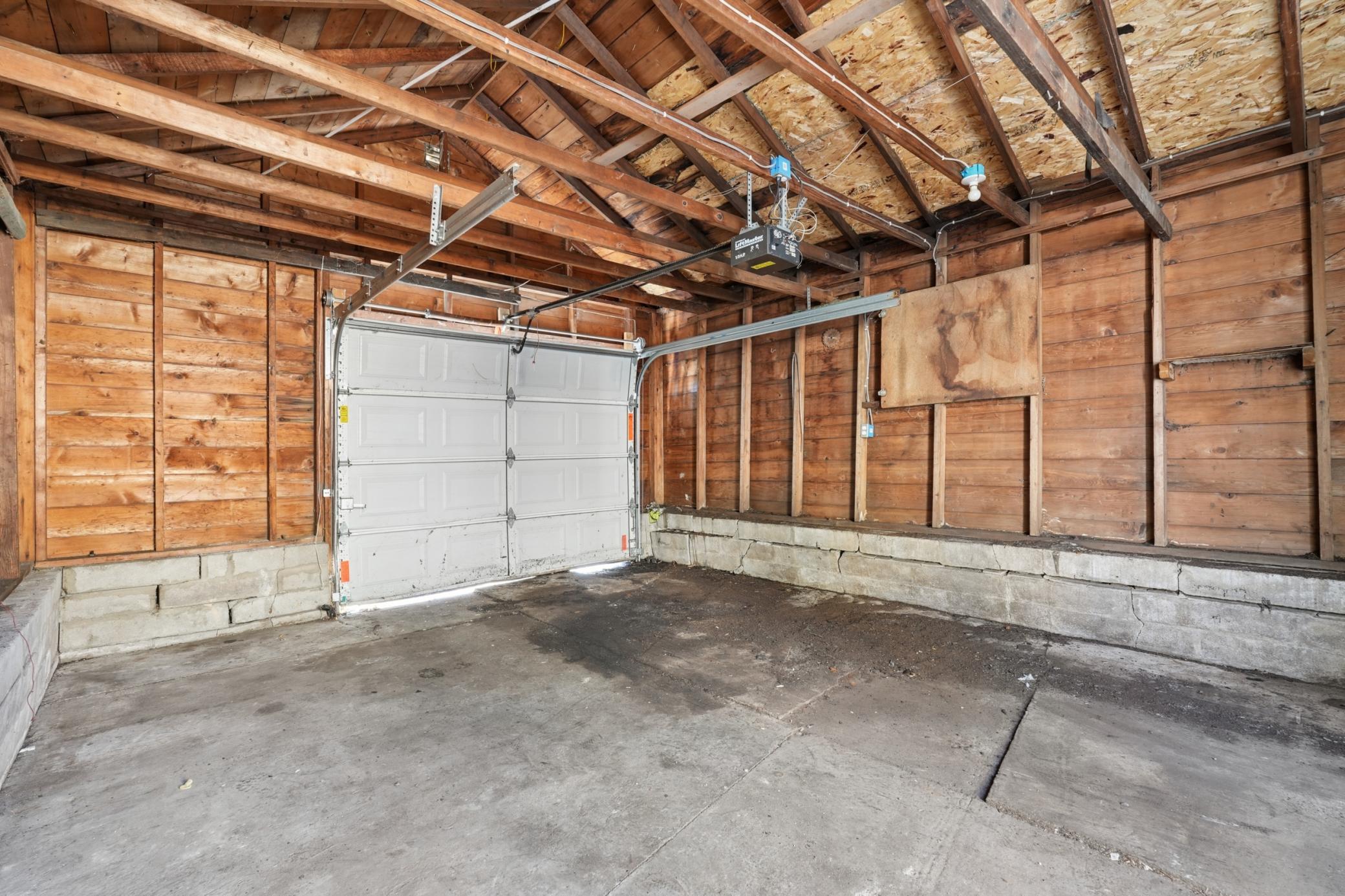 Oversized 1-car detached garage with exposed wood interior and ample storage space.