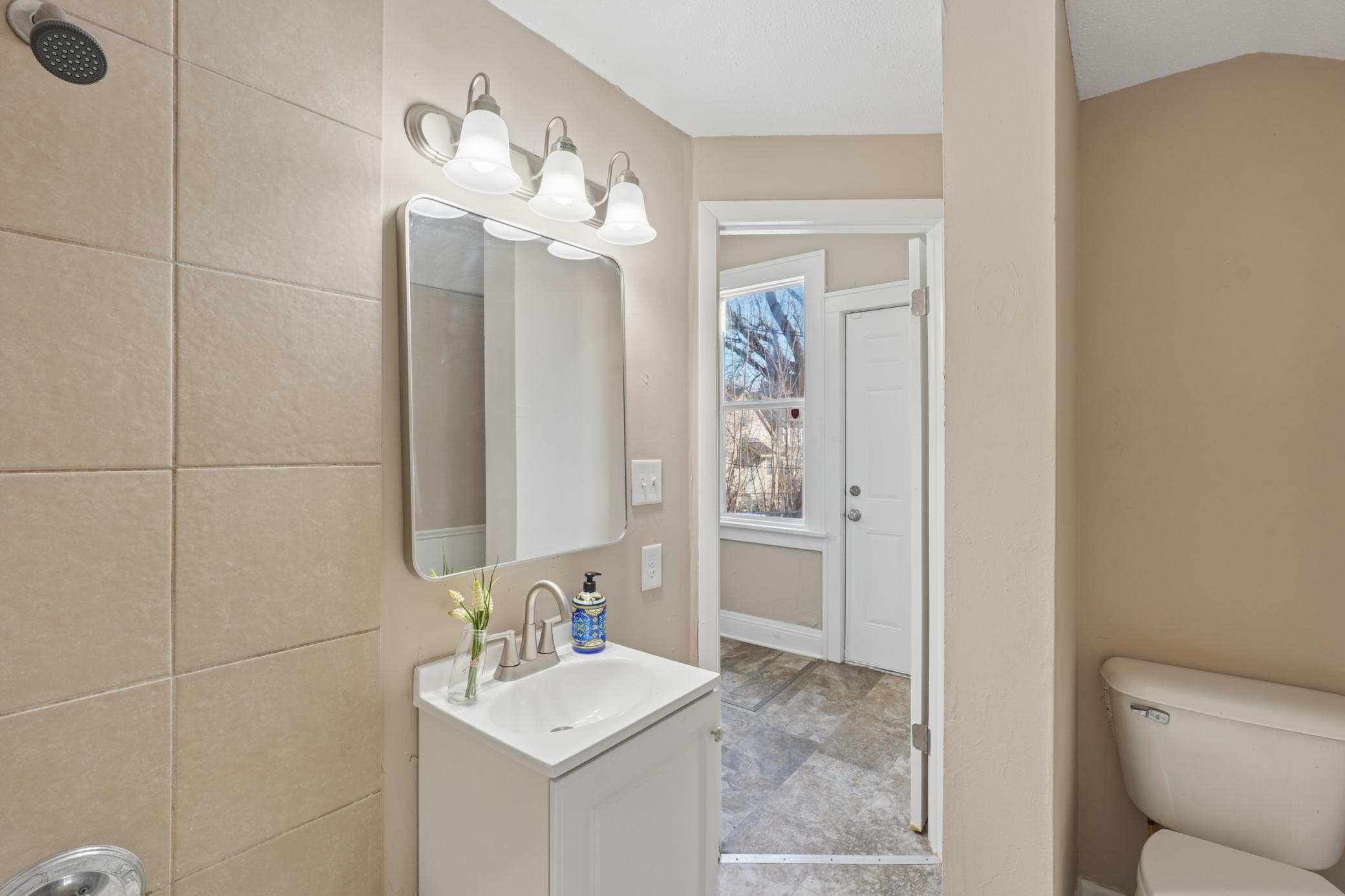 Updated full bathroom featuring modern vanity, updated lighting, and tiled shower surround.