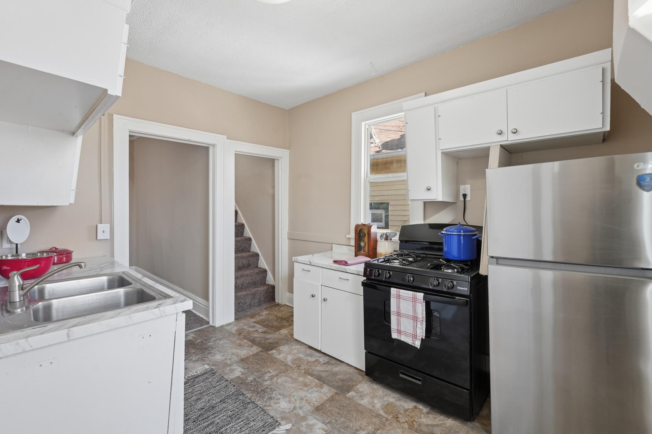 Kitchen with new refrigerator and range, plus access to rear entry.