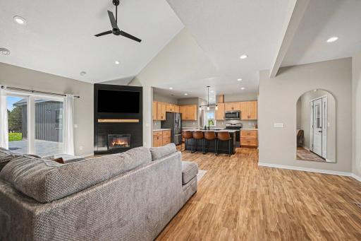 Bright living room with custom clear maple fireplace mantel, open staircase, large windows, and modern main-level flow.