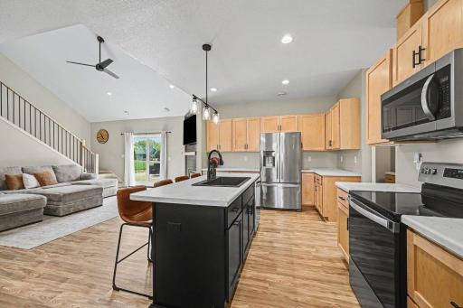 Second kitchen angle shows full appliance suite, maple cabinetry, and open sightlines â 19347 Lake Volney Circle Le Center MN