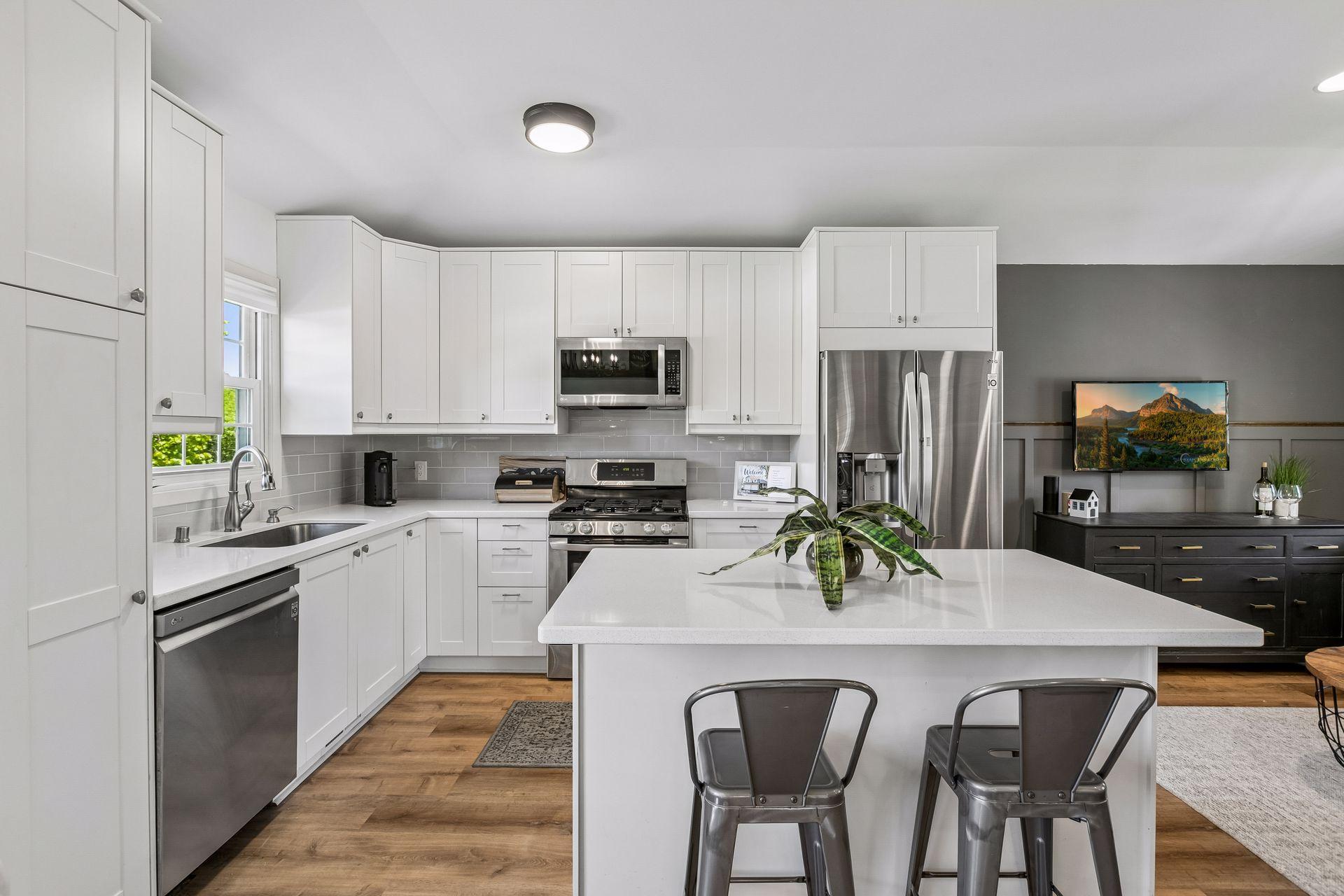 Beautifully renovated kitchen is light and bright with plenty of shaker style cabinetry, updated stainless appliances, quartz countertops and a handy breakfast bar with additional storage.