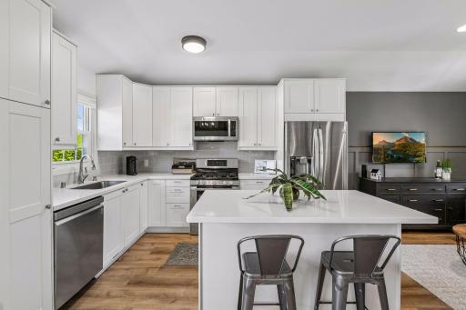 Beautifully renovated kitchen is light and bright with plenty of shaker style cabinetry, updated stainless appliances, quartz countertops and a handy breakfast bar with additional storage.