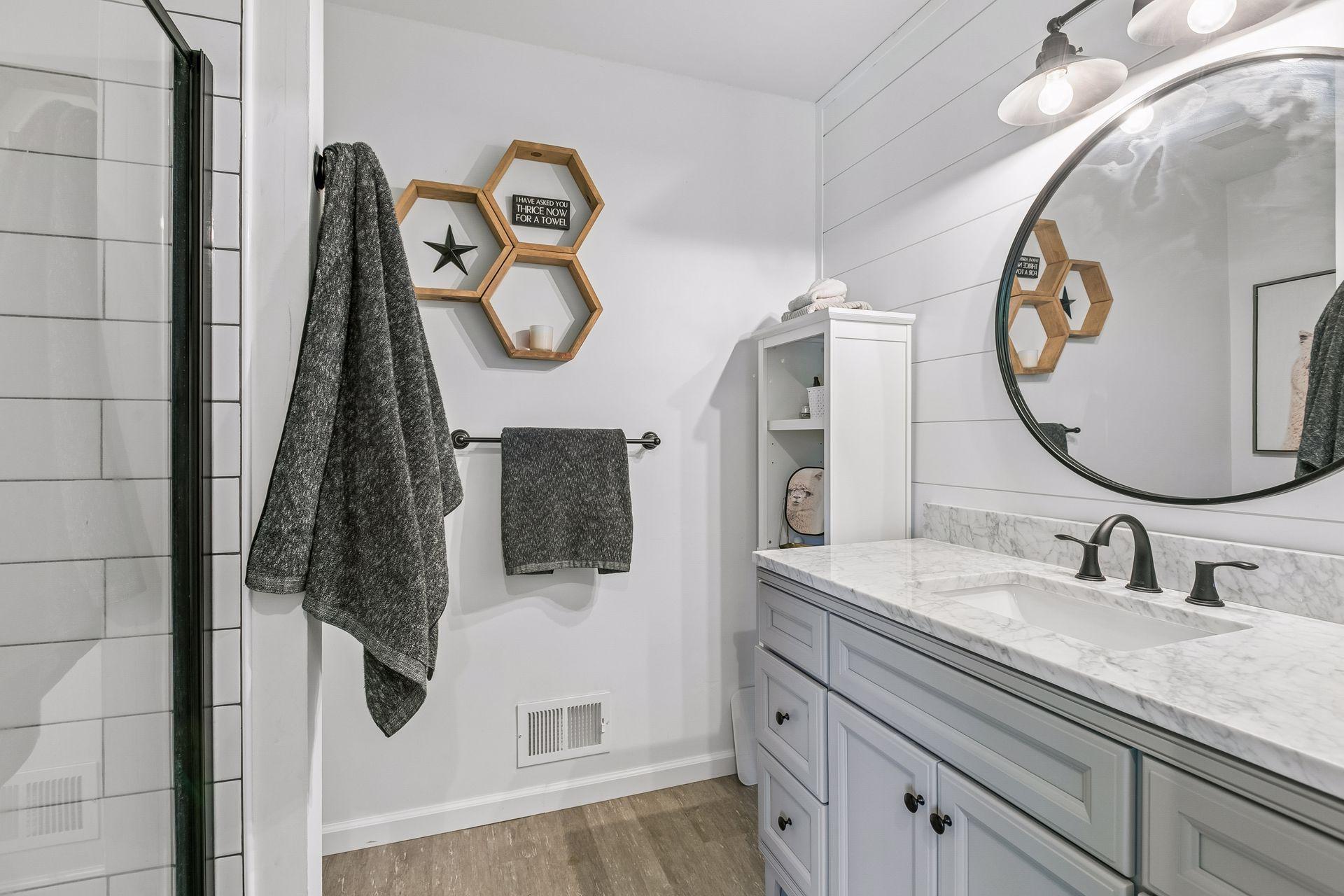 The private owners bath is stylishly updated with a large storage vanity with quartz countertop, updated lighting, neutral subway tile and modern fixtures.