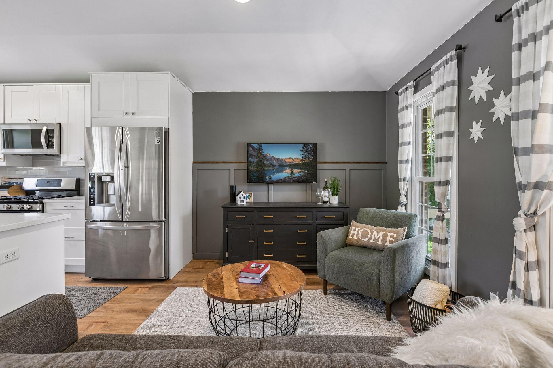 The living area off of the kitchen has two large windows for natural light, solid surface flooring and modern wainscoting for a stylish touch.