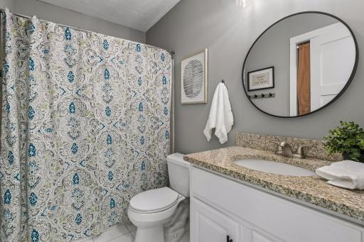 The upper level full bath has an updated storage vanity with stone countertop and updated fixtures.