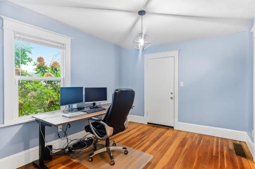 A cozy farmhouse dining room currently used as an office boast beautiful hardwood floors.