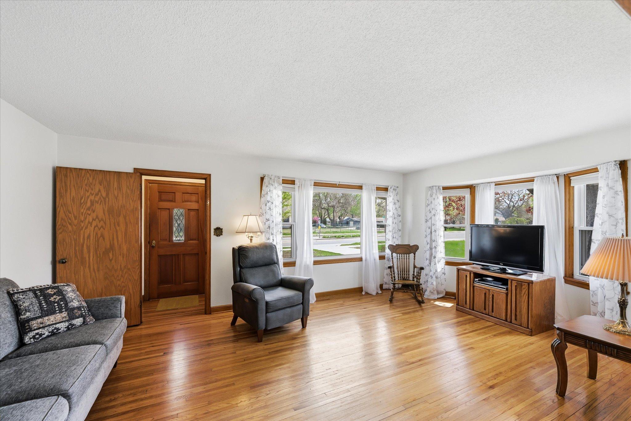 Sun filled living room has original 6 panel wood door. Coat closet in foyer with mail slot