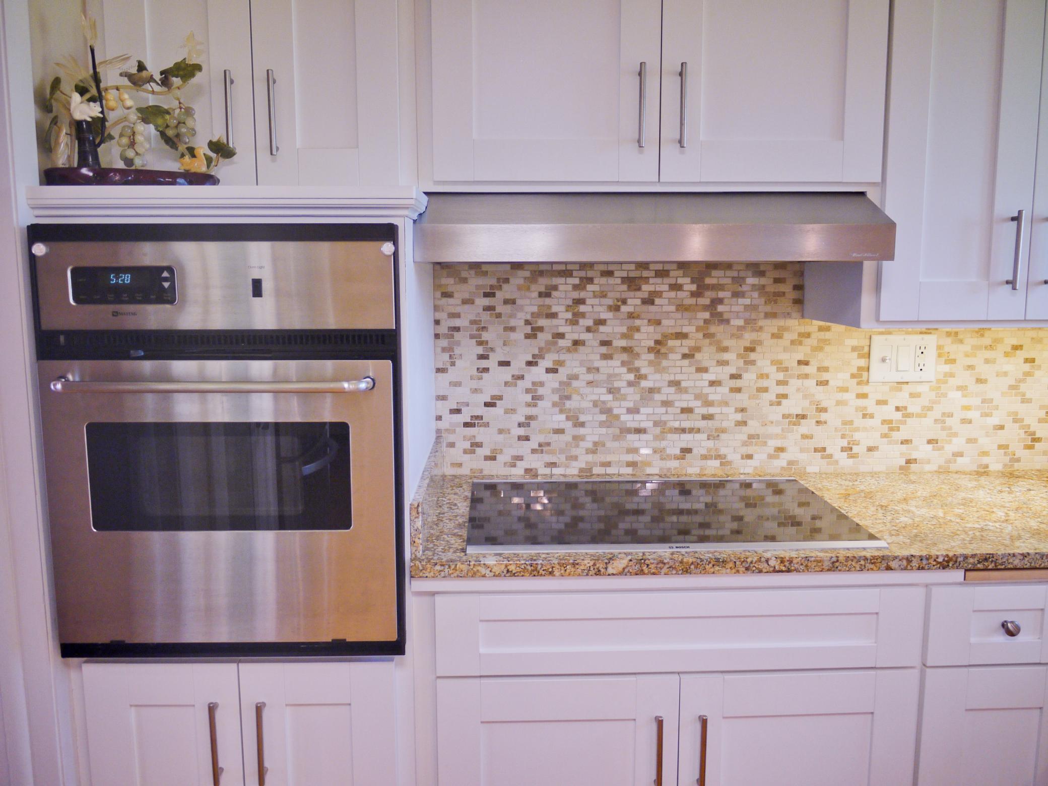 Detail of kitchen prep area showing wall oven, updated cooktop and stainless steel vent hood venting to the exterior.jpg