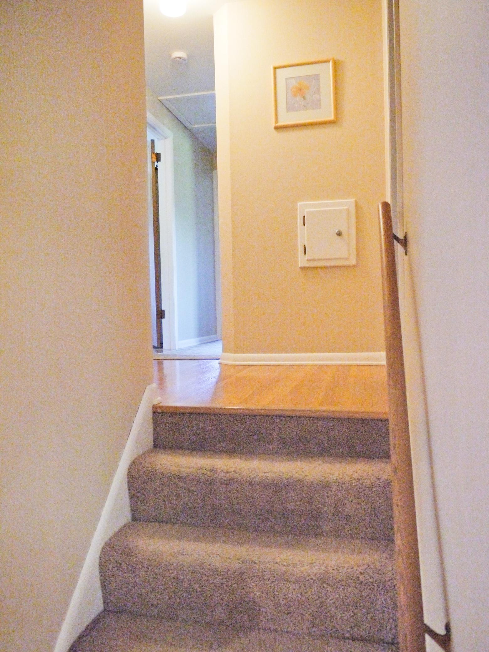 Half flight of stairs leading to bedroom and bath area with solid oak floors and laundry shute.jpg