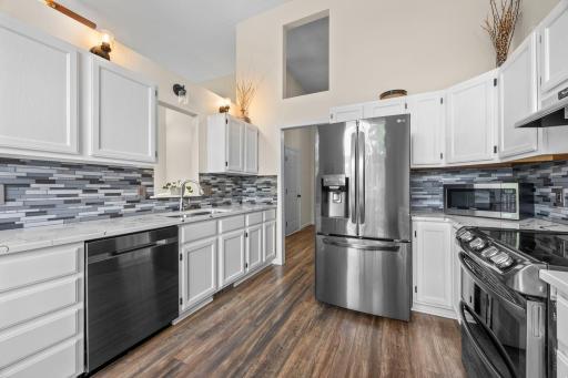 Black stainless steel appliances anchor a sleek, modern kitchen with tile backsplash.