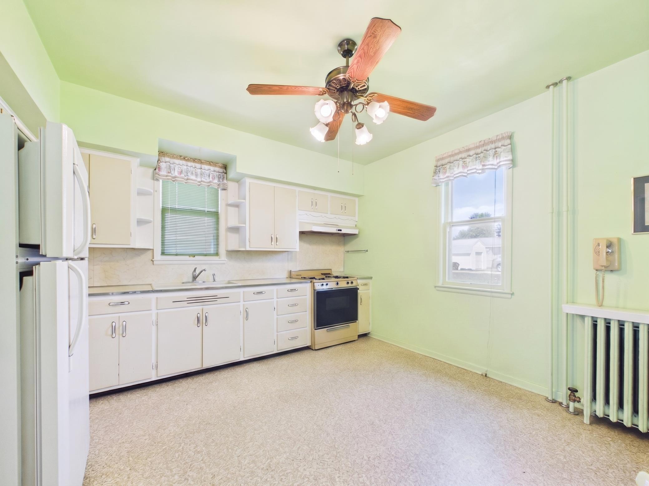 Bright kitchen space with windows, storage, and renovation potential.