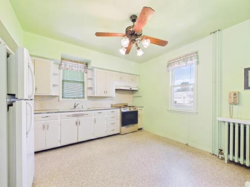 Bright kitchen space with windows, storage, and renovation potential.