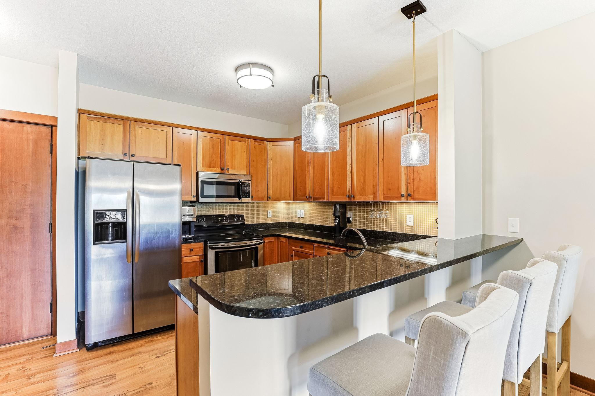 Large open kitchen with stainless steel appliances, granite tops and beautiful wood cabinetry.