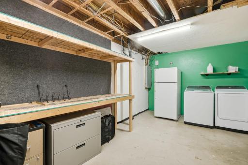 Huge laundry room with built-in shelving and the fridge stays.