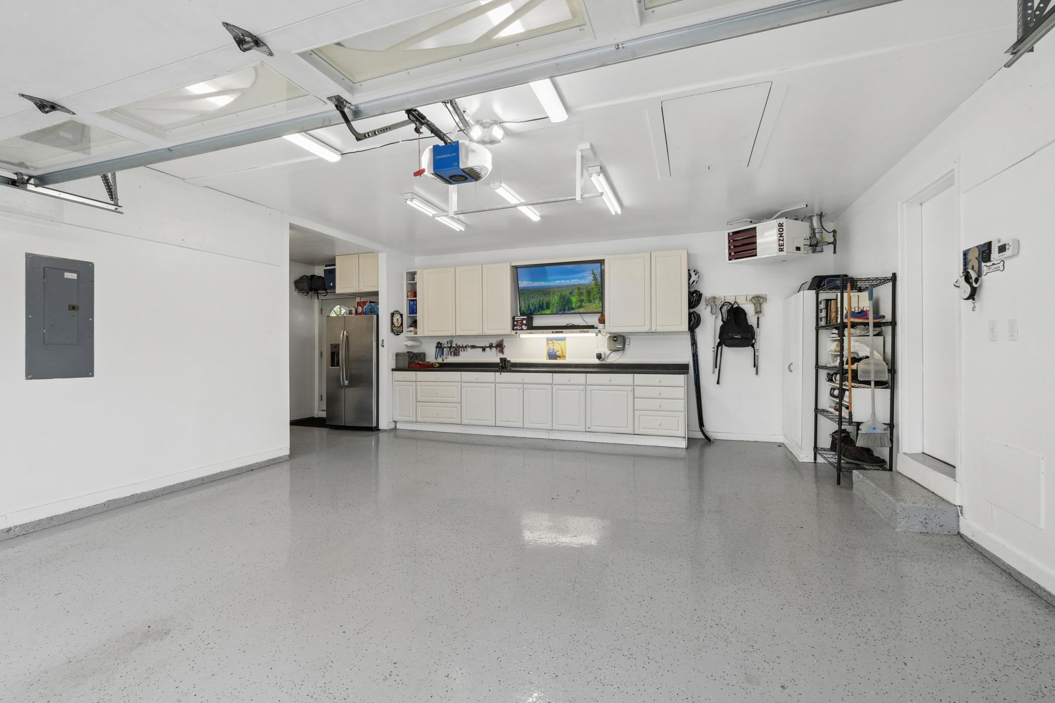 Wonderful garage setup featuring heat, epoxy floors, a media/work bench area, pull-down attic storage, and seamless access to both the front and backyark. Perfect for any garage enthusiast.