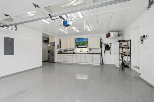 Wonderful garage setup featuring heat, epoxy floors, a media/work bench area, pull-down attic storage, and seamless access to both the front and backyark. Perfect for any garage enthusiast.