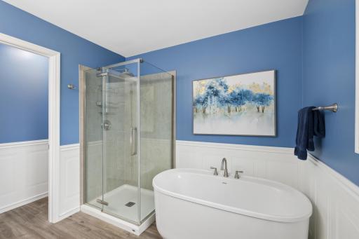 Primary updated bathroom with soaking tub and tiled shower.